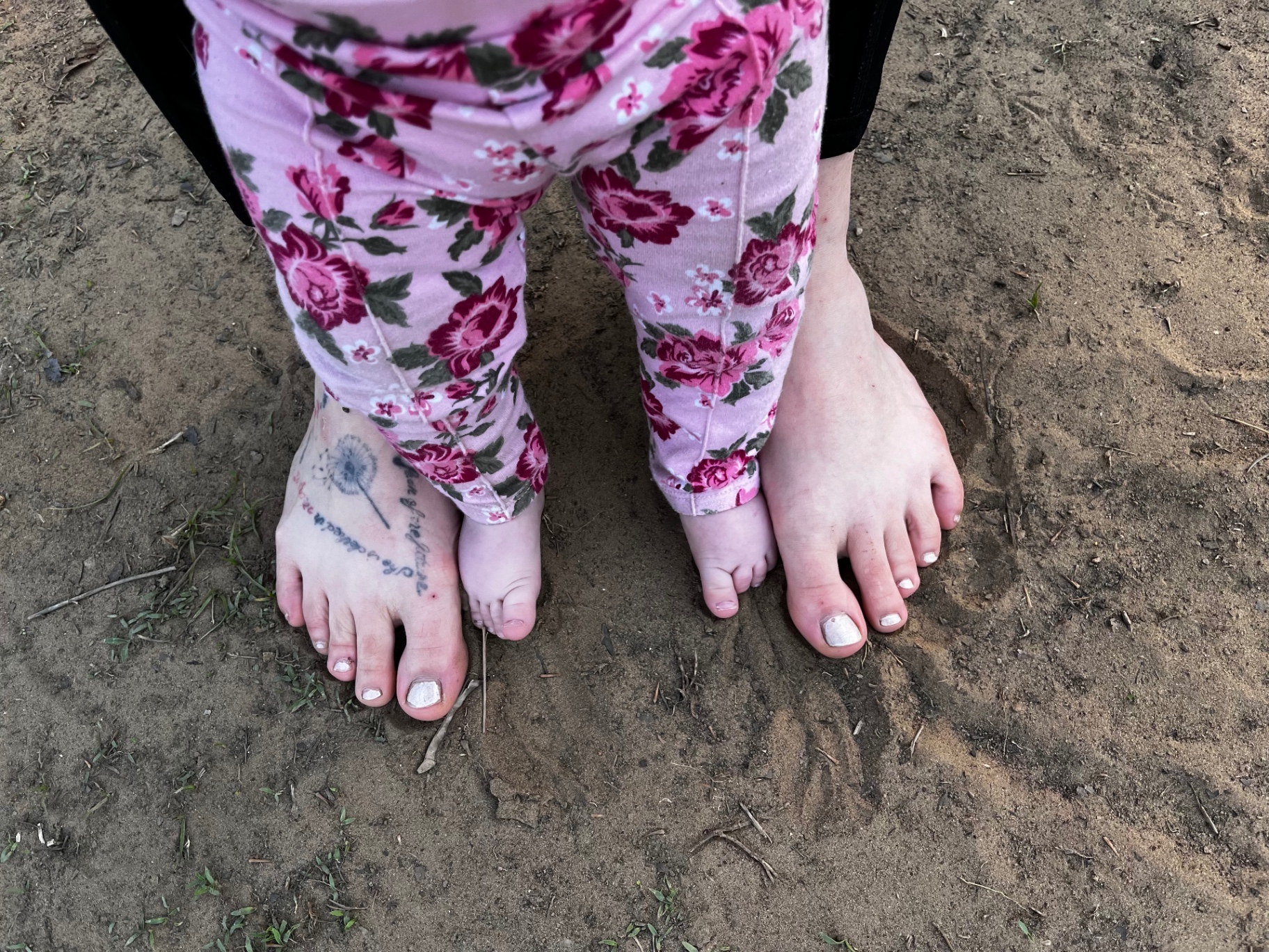 Bare feet walking together through grass beside a path